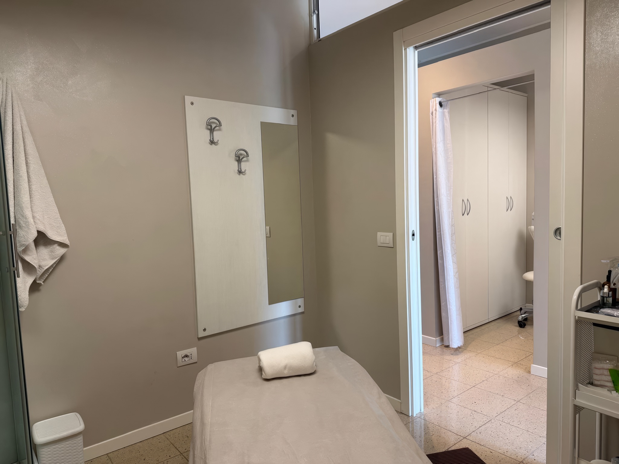 La cabina trattamenti con lettino, specchio e la vista sulla cabina successiva
