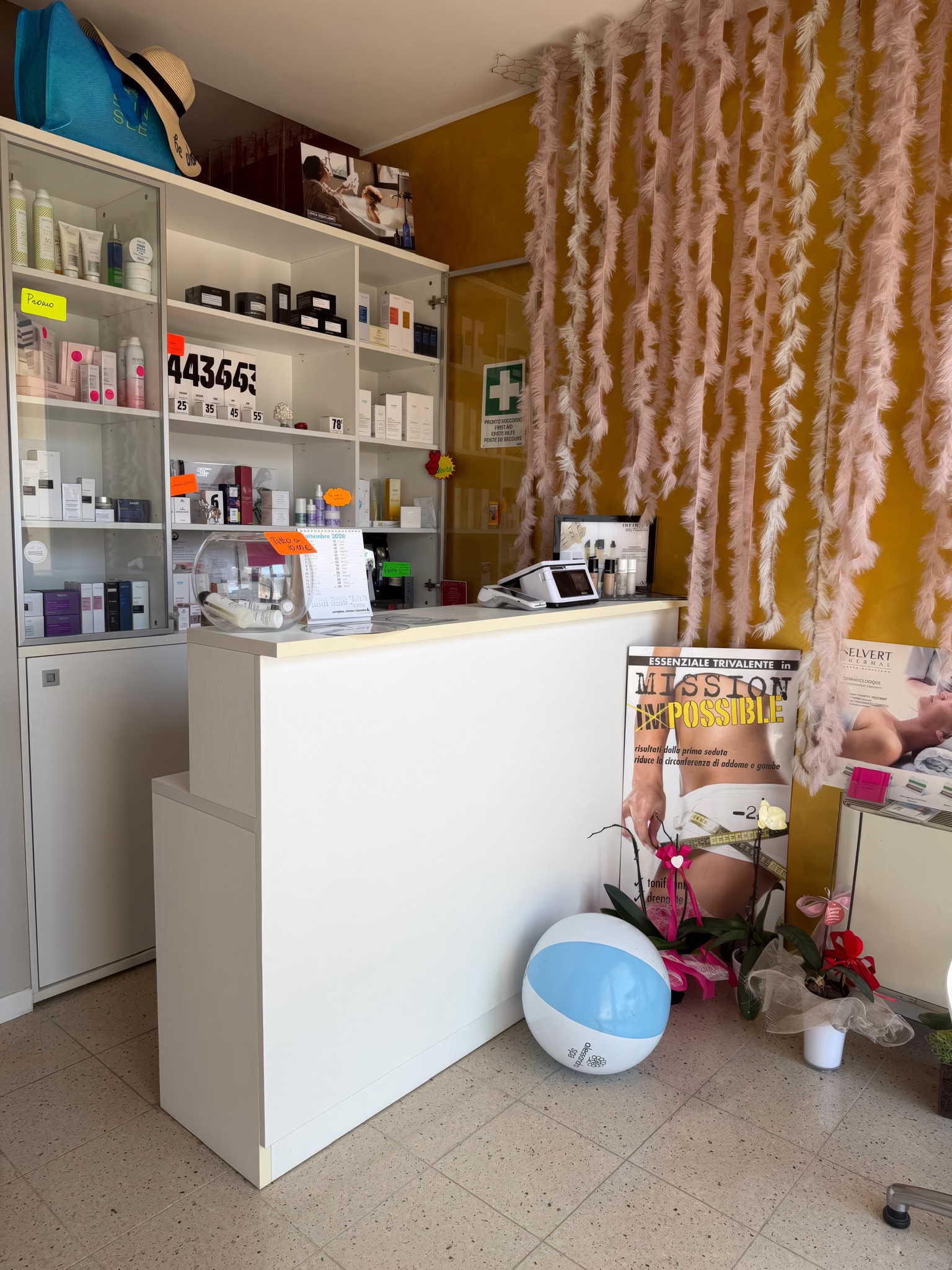 La reception con il banco bianco, la parete oro e la tenda di piume rosa